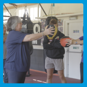 person holding a medicine ball and doing exercises in a boxing gym