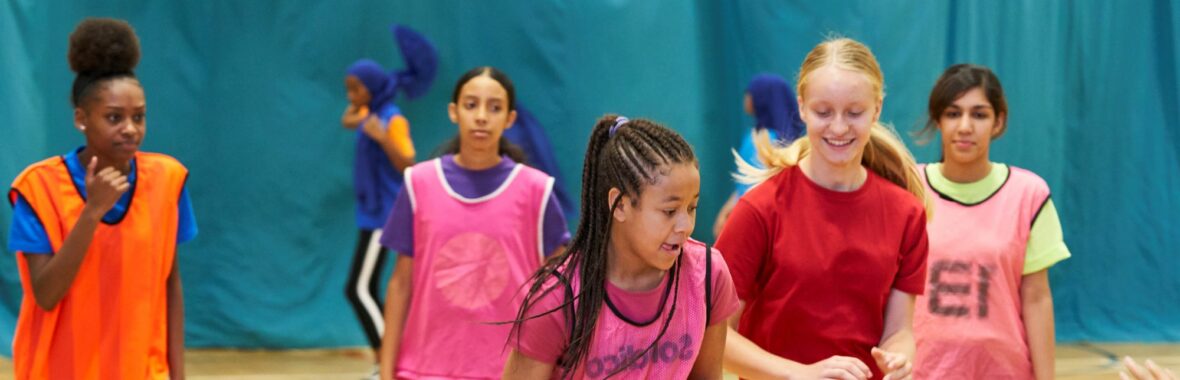 group of girls playing basketball in a sports hall