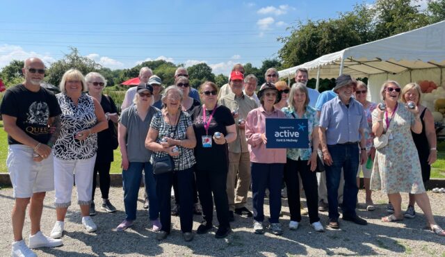 Group of people standing in the sun holding a 'supported by Active Kent & Medway' banner