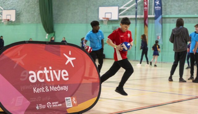 young person running with a ball in a sports hall