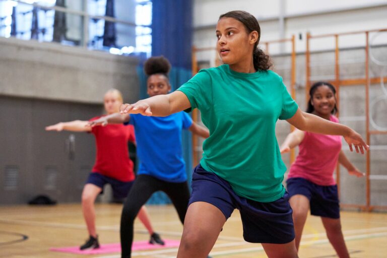 young people doing yoga in sports hall