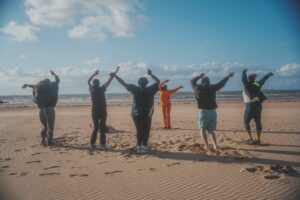 group of women on the beach with hands in the air