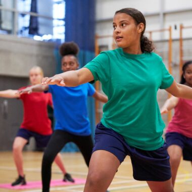 young people doing yoga in sports hall