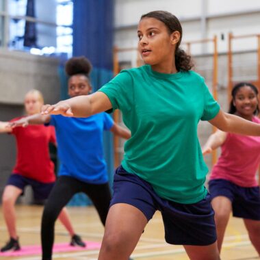 young people doing yoga in sports hall