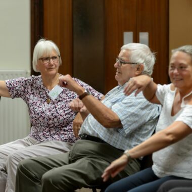 older people seated and moving their arms