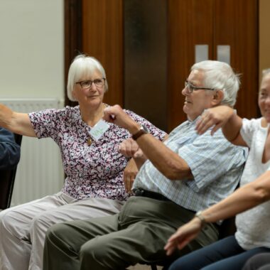 older people seated and moving their arms
