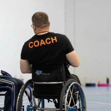 Basketball coach in a wheelchair speaking to young person in wheelchair