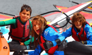 children smiling sat in small boats on the river