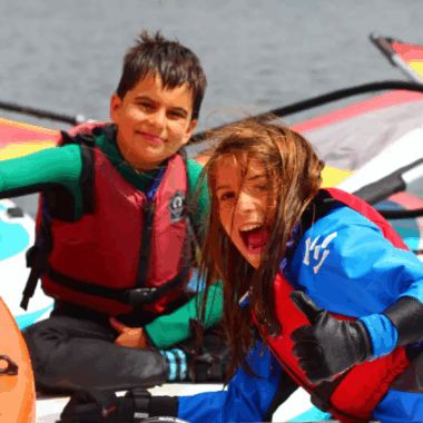 children smiling sat in small boats on the river