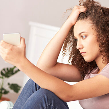 Young person sat with phone in their hand