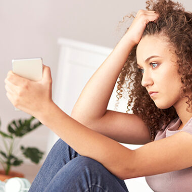 Young person sat with phone in their hand