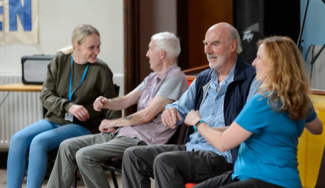 two men sitting in group doing seated exercises