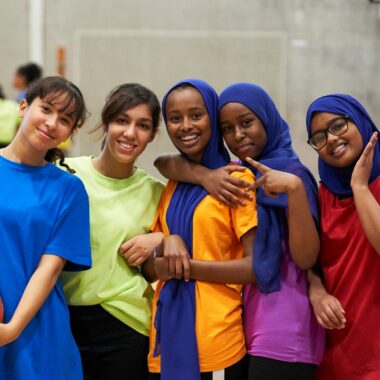 group of girls standing in a sports hall smiling