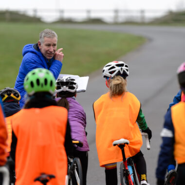 Coach speaking to a group of children on bikes