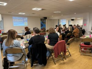 group of people sat in a room listening to a speaker