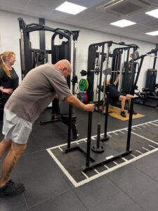 A man pushing a sledge across the floor of the gym