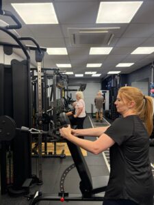 An instructor setting up the gym equipment with a lady standing in the background
