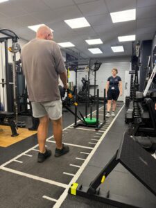 A man pulling a sledge across the floor of the gym