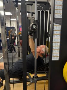 A man lying back and using a bench press in the gym